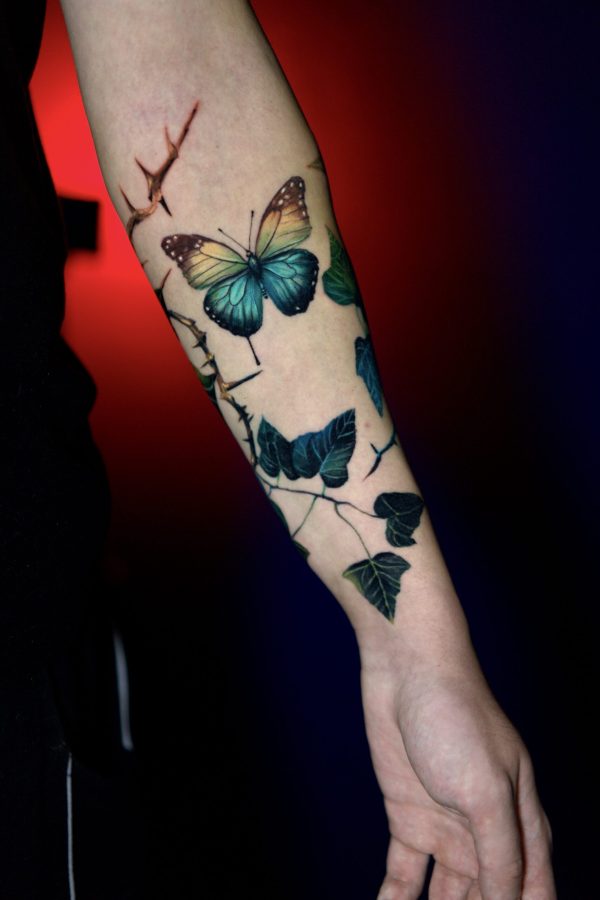 Realistic butterfly color tattoo with leaves and thorns on forearm By Mihaly Forgony
