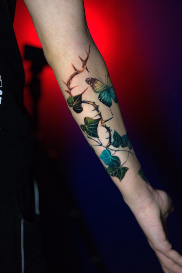 Realistic butterfly color tattoo with leaves and thorns on forearm, done By Mihaly Forgony